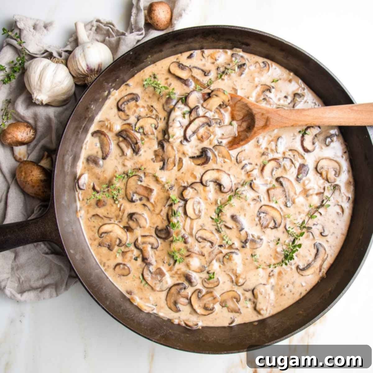 Close-up of tender, sliced mushrooms in a creamy, rich brown sauce in a cast iron skillet, ready to be served.