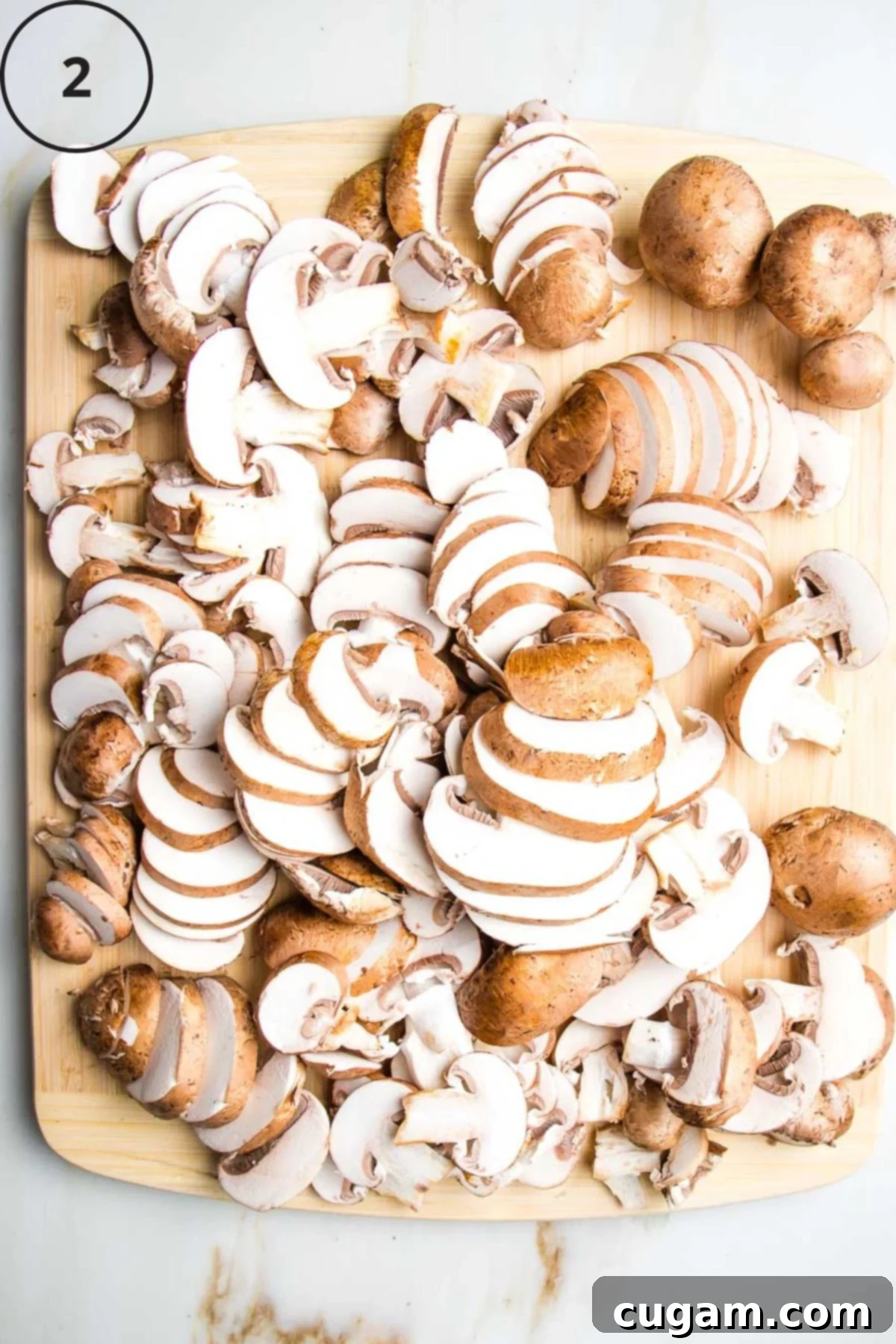 Perfectly sliced cremini (baby bella) mushrooms arranged on a rustic wooden cutting board, with their stems still attached.