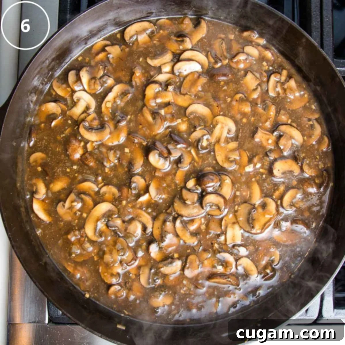 Sliced mushrooms in a rich brown sauce simmering in a cast iron skillet after balsamic vinegar and wine have been added.