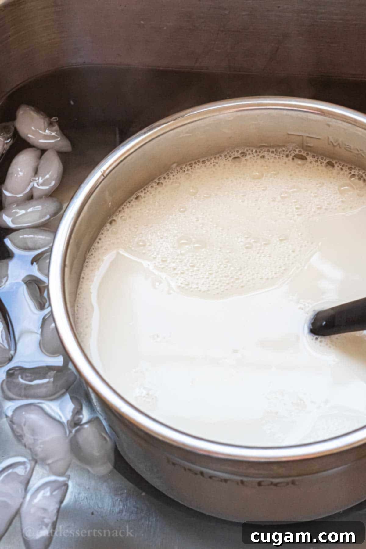 Metal pot of milk in sink of ice water.