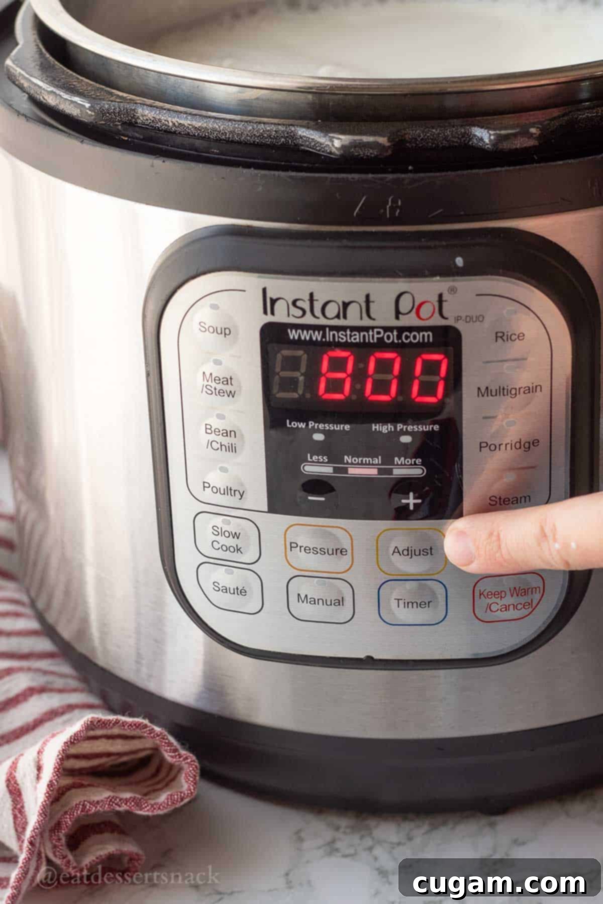 Finger next to Adjust button on instant pot.