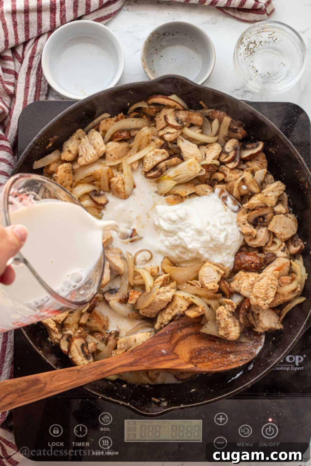 Pouring the milk and flour mixture slowly into a frying pan with cooked chicken, onion, and mushrooms, while stirring.