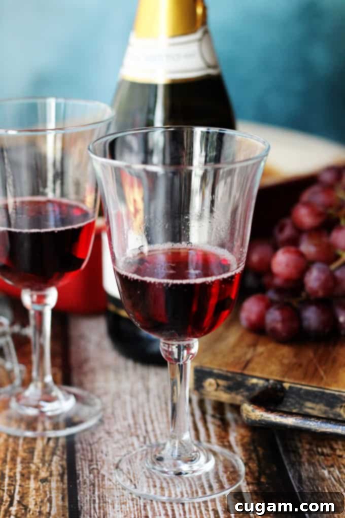 Glasses of sparkling Brachetto Italian dessert wine, with its distinctive red hue, alongside a bottle and fresh grapes, suggesting a celebration.