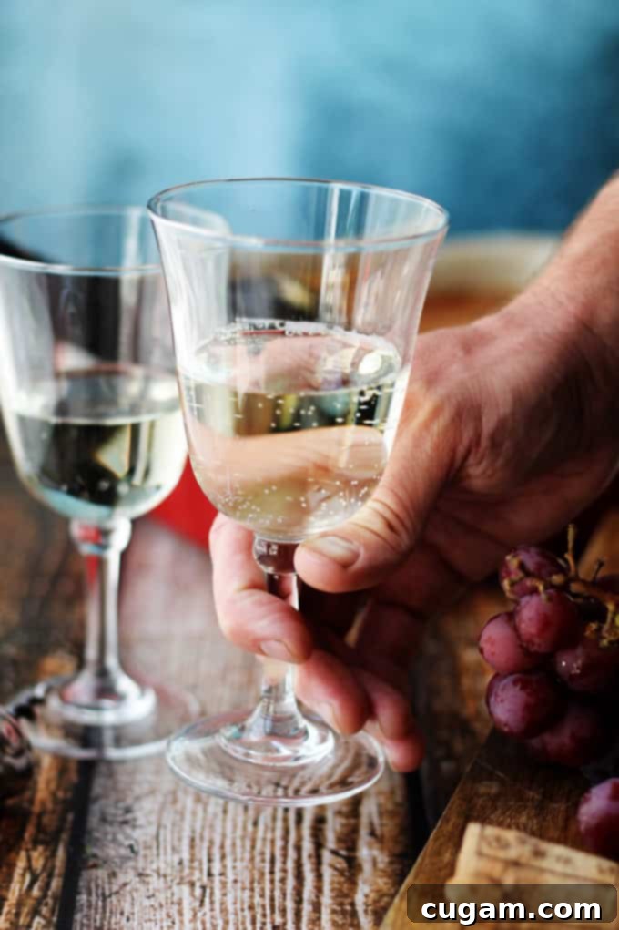 A hand gently holding a glass of Moscato d'Asti, highlighting its clear, appealing color and delicate nature.