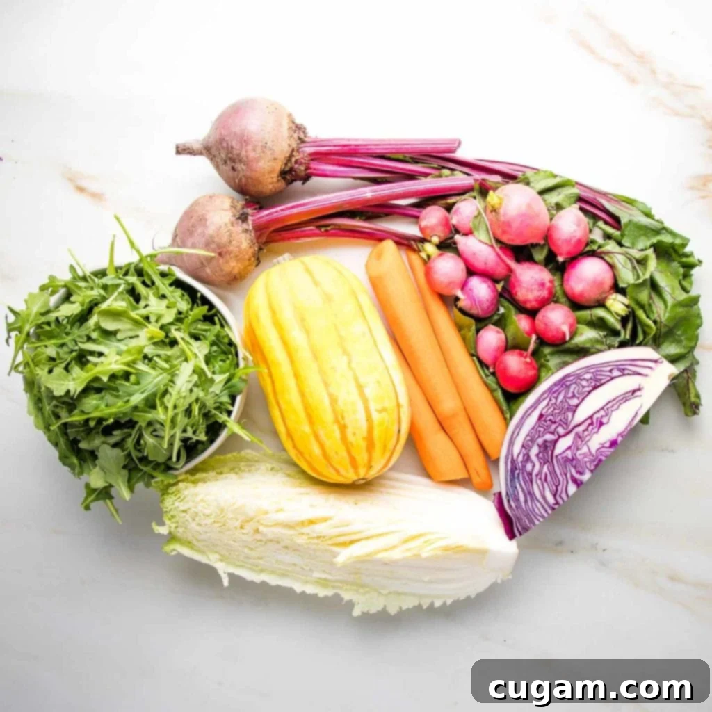Ingredients for rainbow salad before chopping: small bowl of arugula, ¼ green cabbage, ¼ purple cabbage, delicata squash, 2 red beets with greens, radishes, 3 peeled carrots.