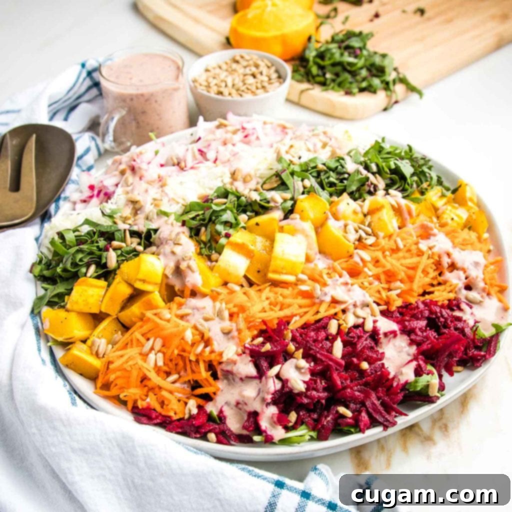 Finished shredded rainbow salad on a white plate, drizzled with pink dressing and sprinkled with sunflower seeds.