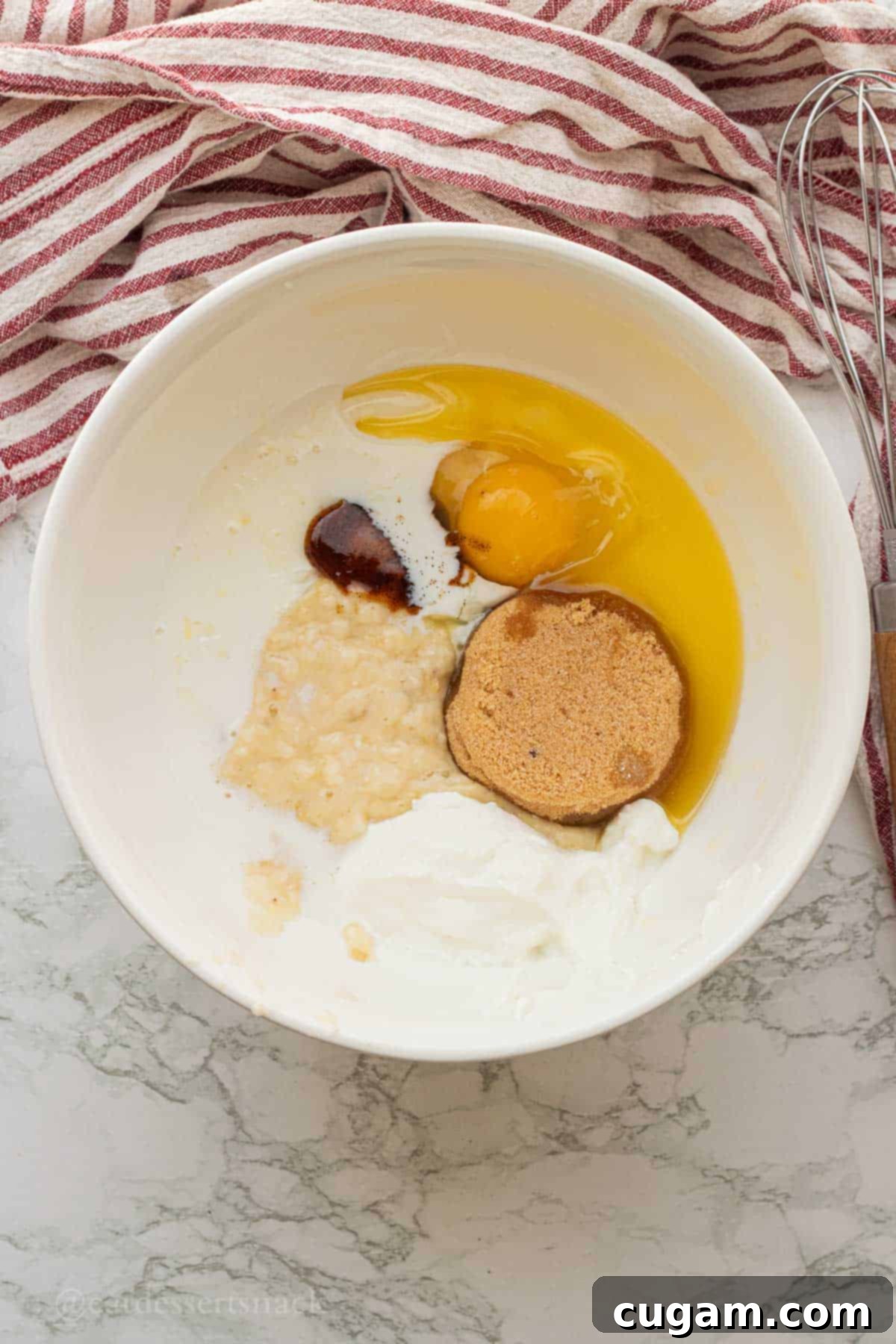 Brown sugar, egg, vanilla, banana, sour cream in white bowl.