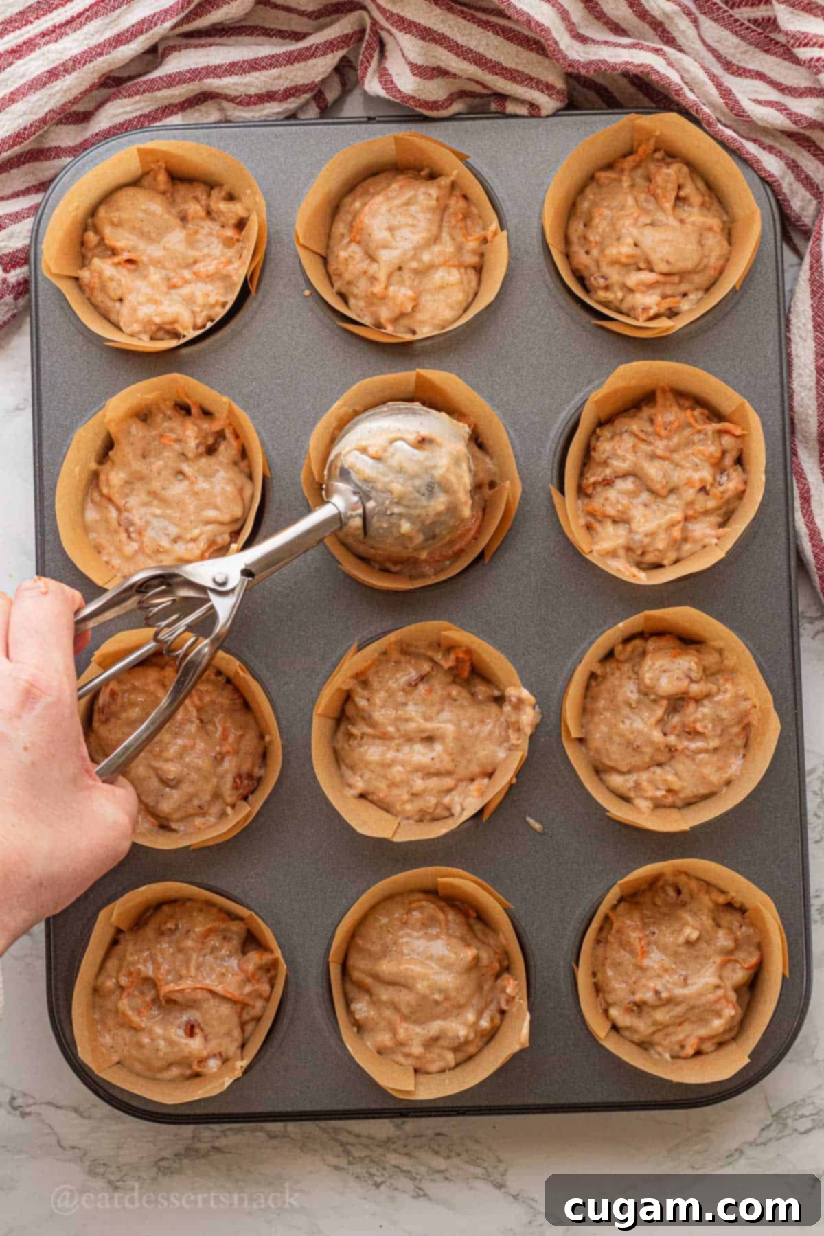 Scooping banana carrot batter into muffin tin.