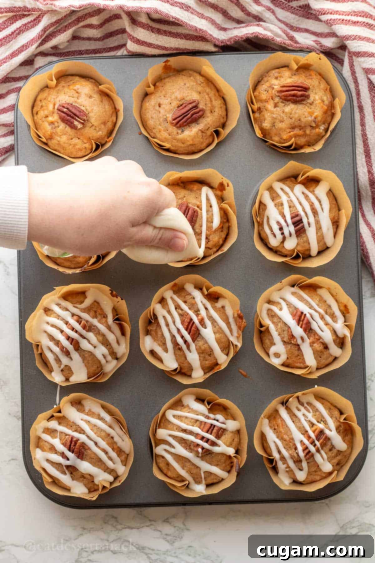Drizzling icing over baked carrot banana muffins