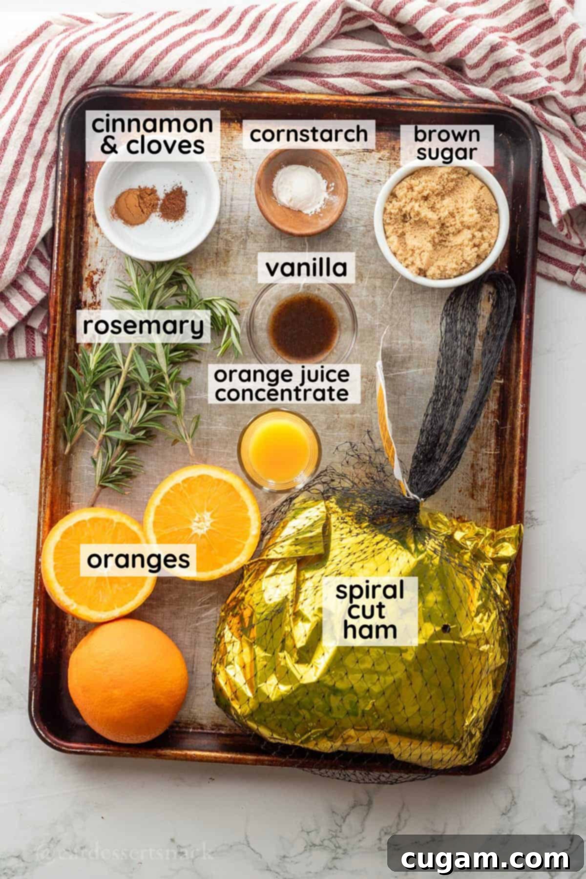 Labeled bowls containing orange zest, brown sugar, orange juice, cinnamon, and cornstarch laid out on a metal baking sheet for the homemade ham glaze.
