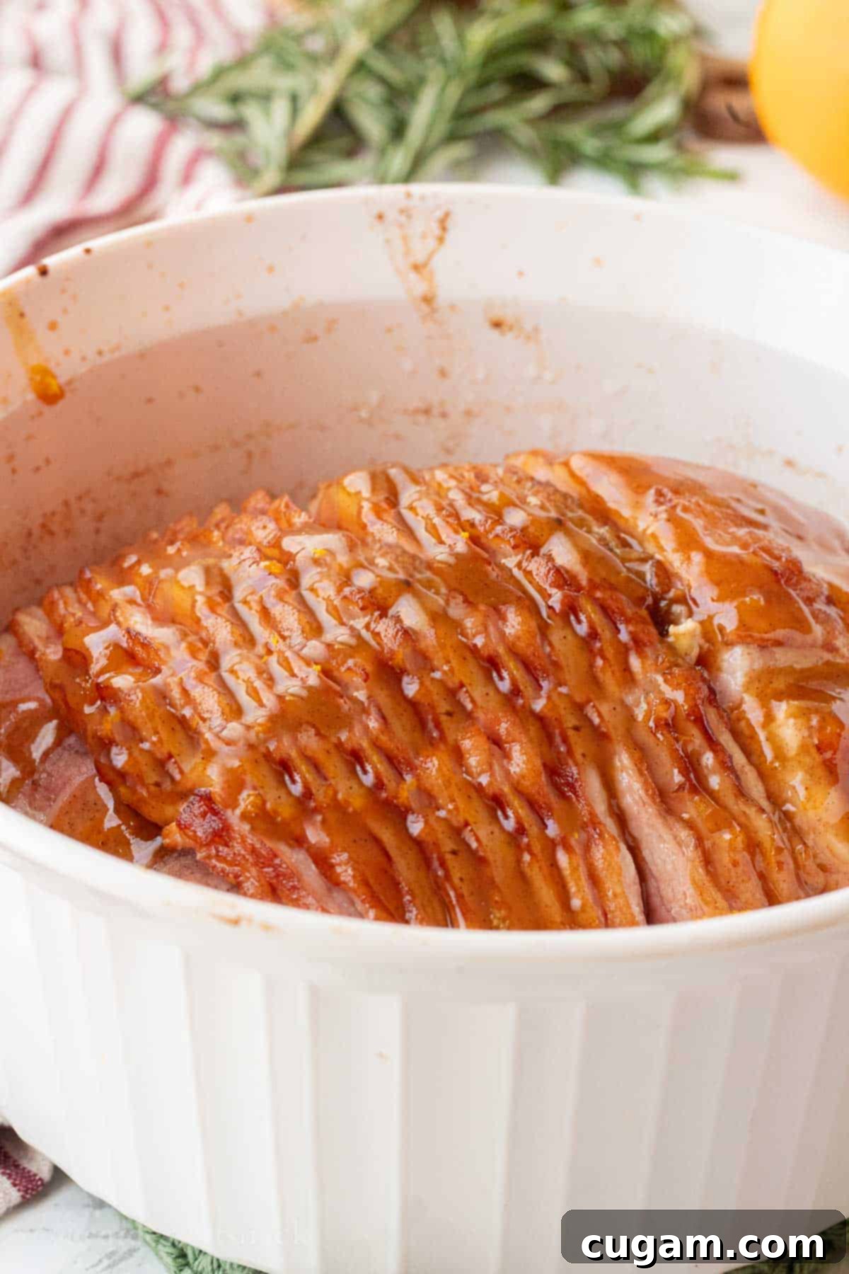 Cooked unglazed spiral ham resting in a white baking dish, ready for glazing.