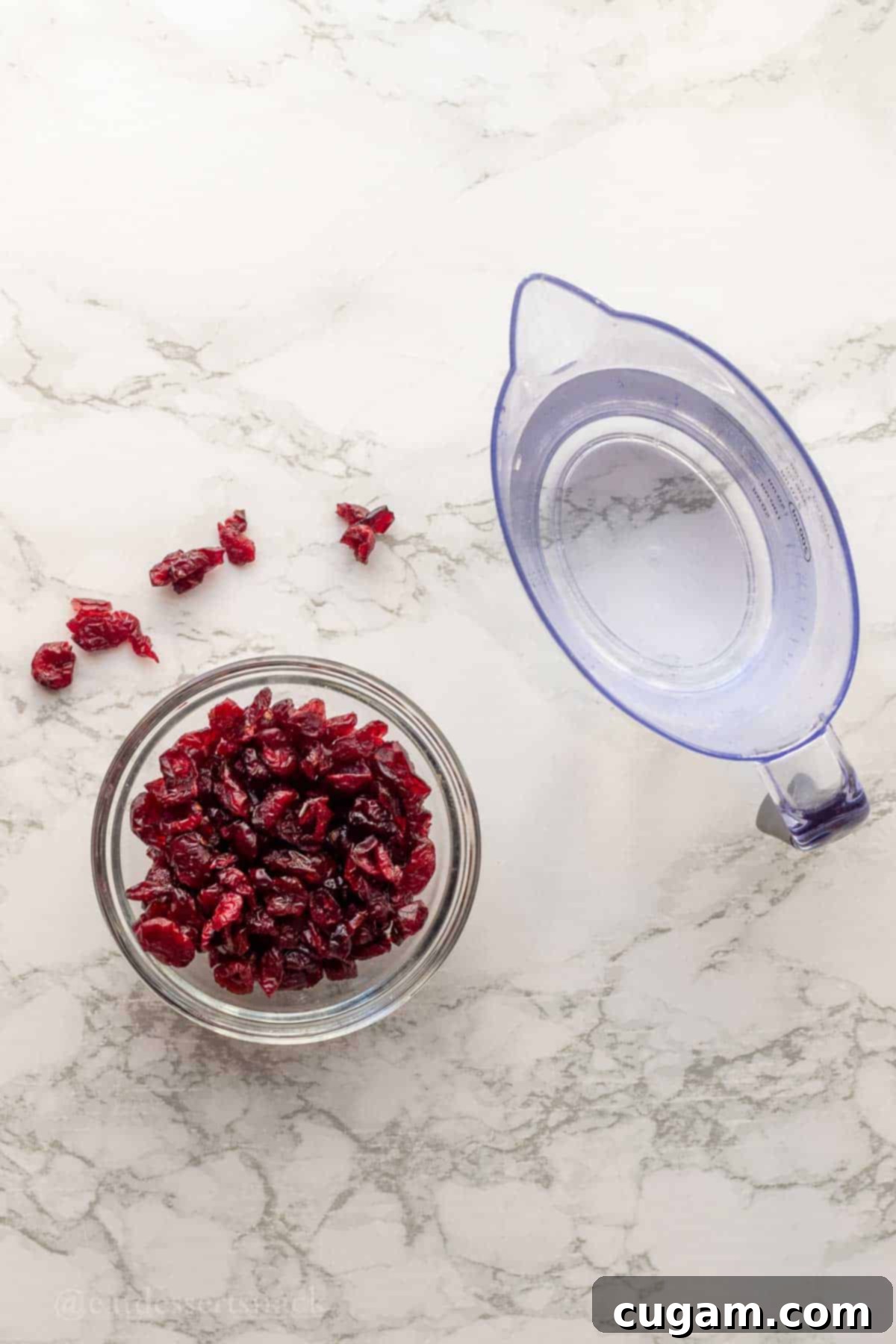 Glass bowl of cranberries and water soaking on a marble countertop.