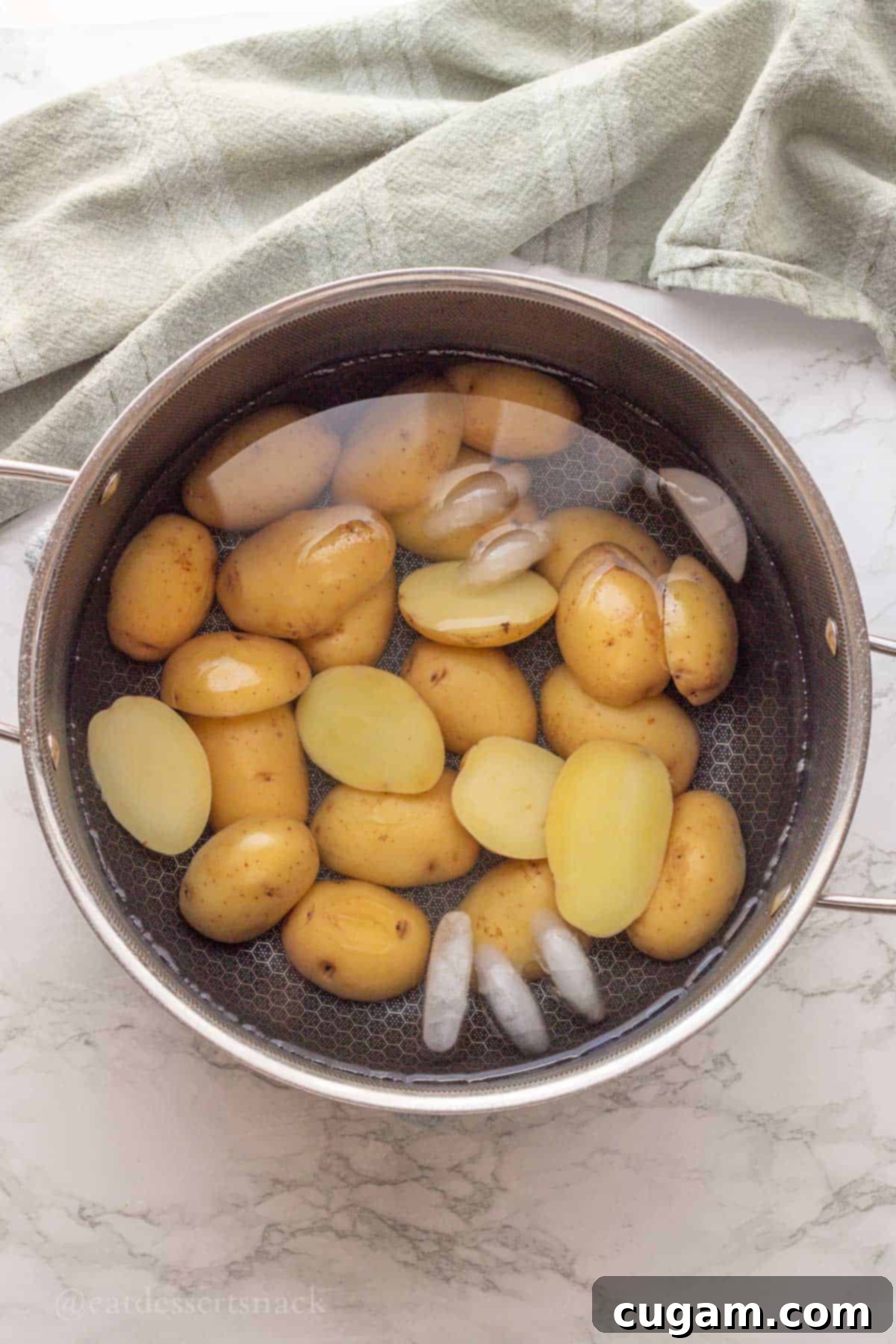 Sliced cooked baby potatoes in ice bath.