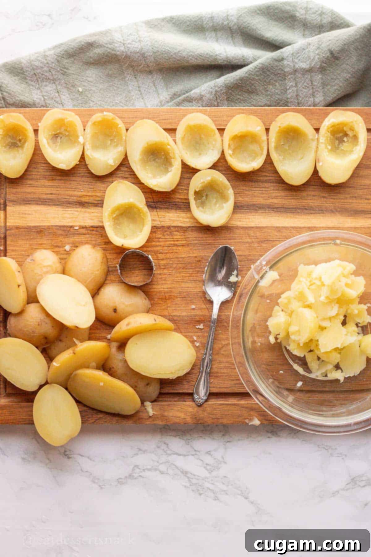 Hollowed out cooked baby potatoes on wood cutting board.