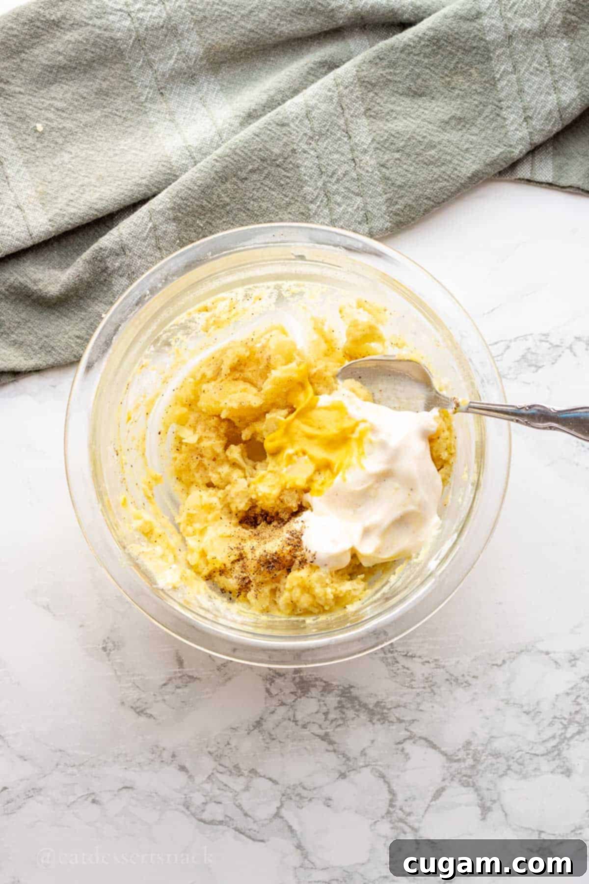 Mustard, mayo, seasonings in bowl of potatoes.