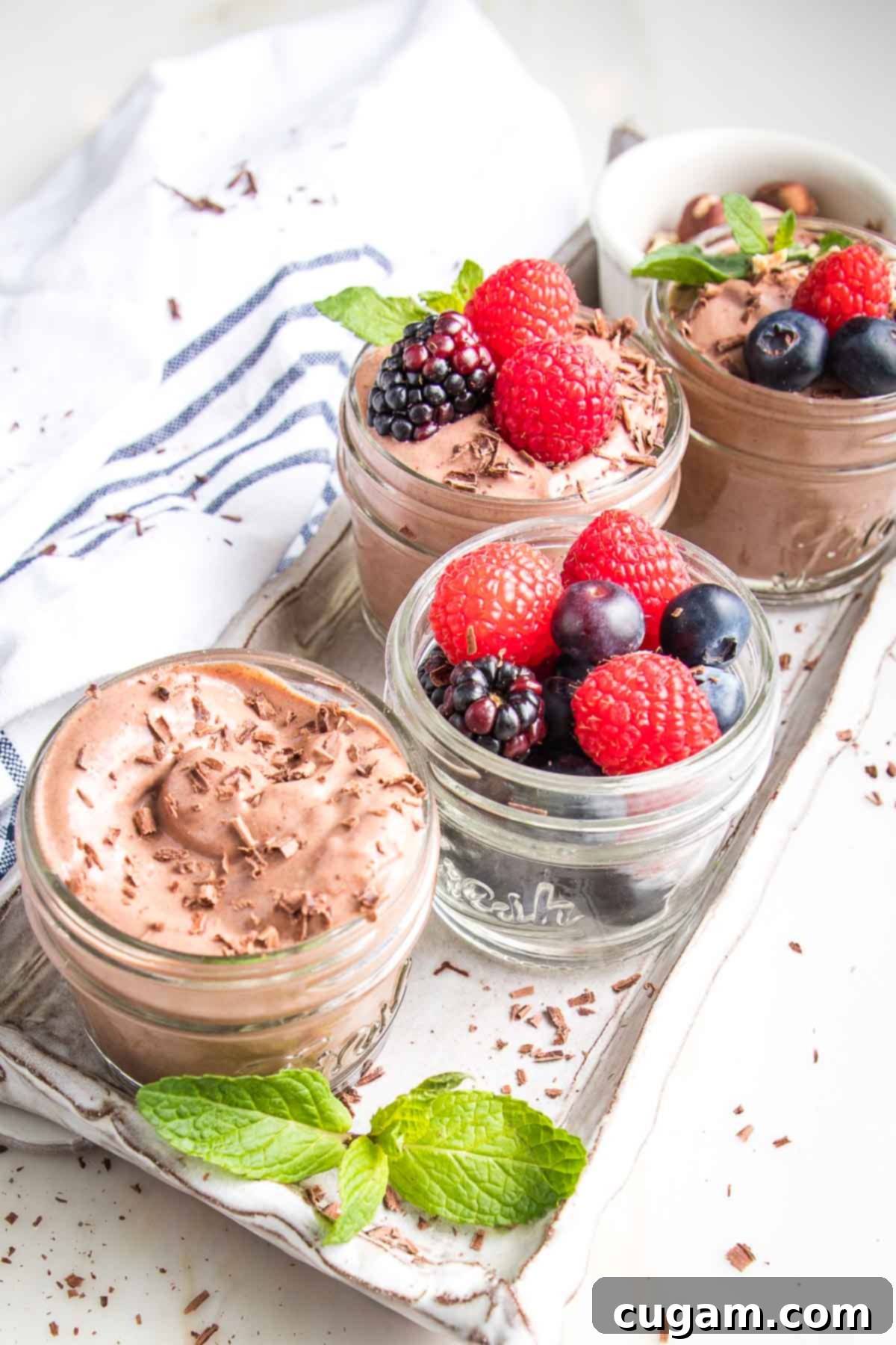 Vegan chocolate pudding in small glass jars with berries, chocolate shavings and fresh mint.