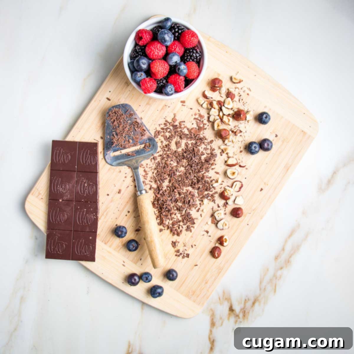 Dark chocolate bar with some shavings, hazelnuts and berries on a wooden board.