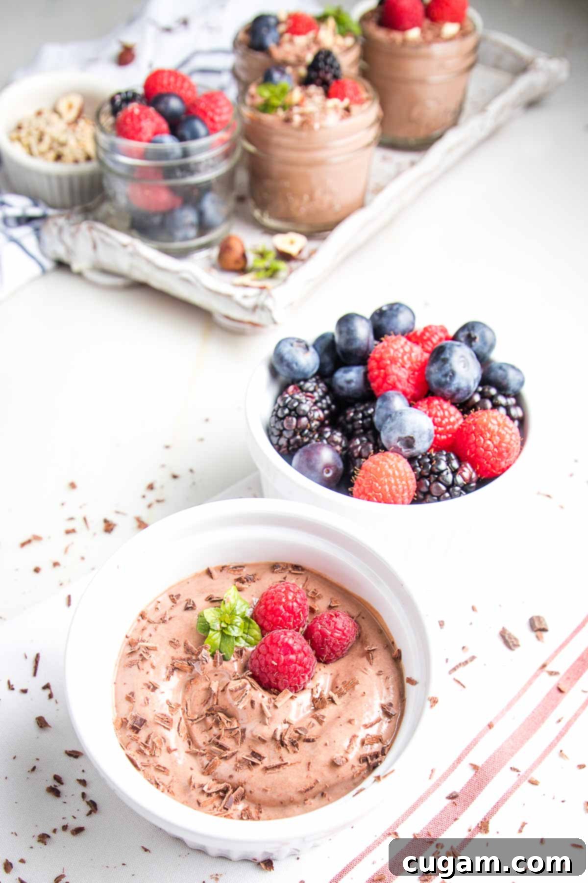 Chocolate pudding in a small bowl with chocolate shavings and berries.