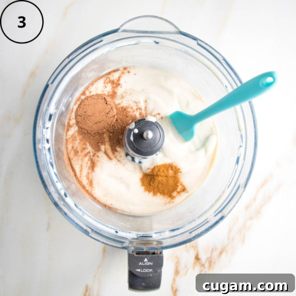 Creamy tofu sprinkled with cocoa powder in the bowl of a food processor.