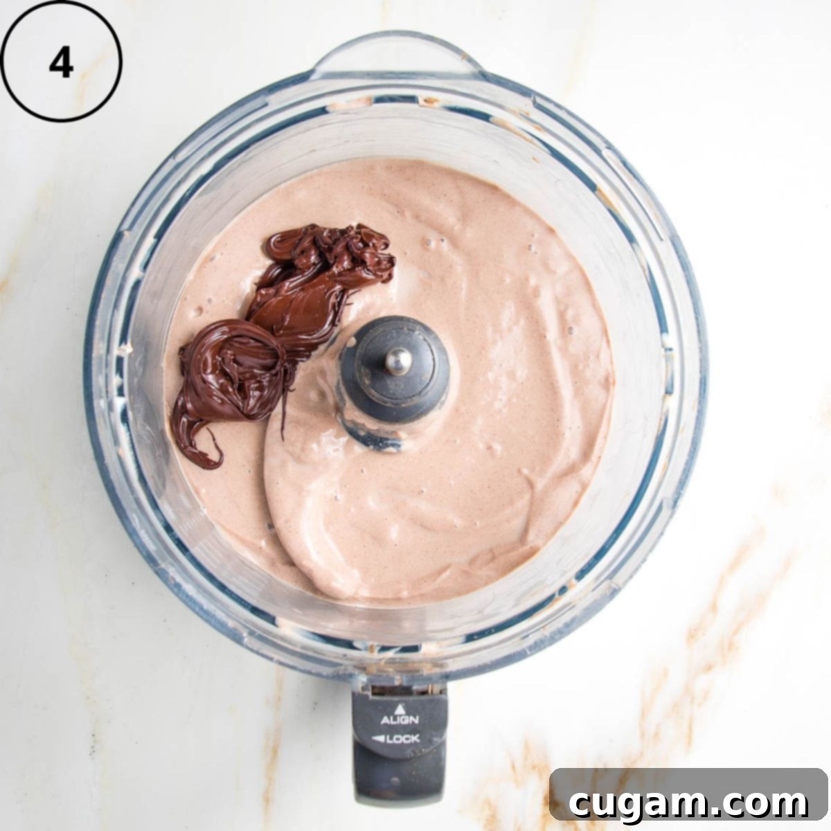 Creamy chocolate pudding plus melted chocolate in the bowl of a food processor.