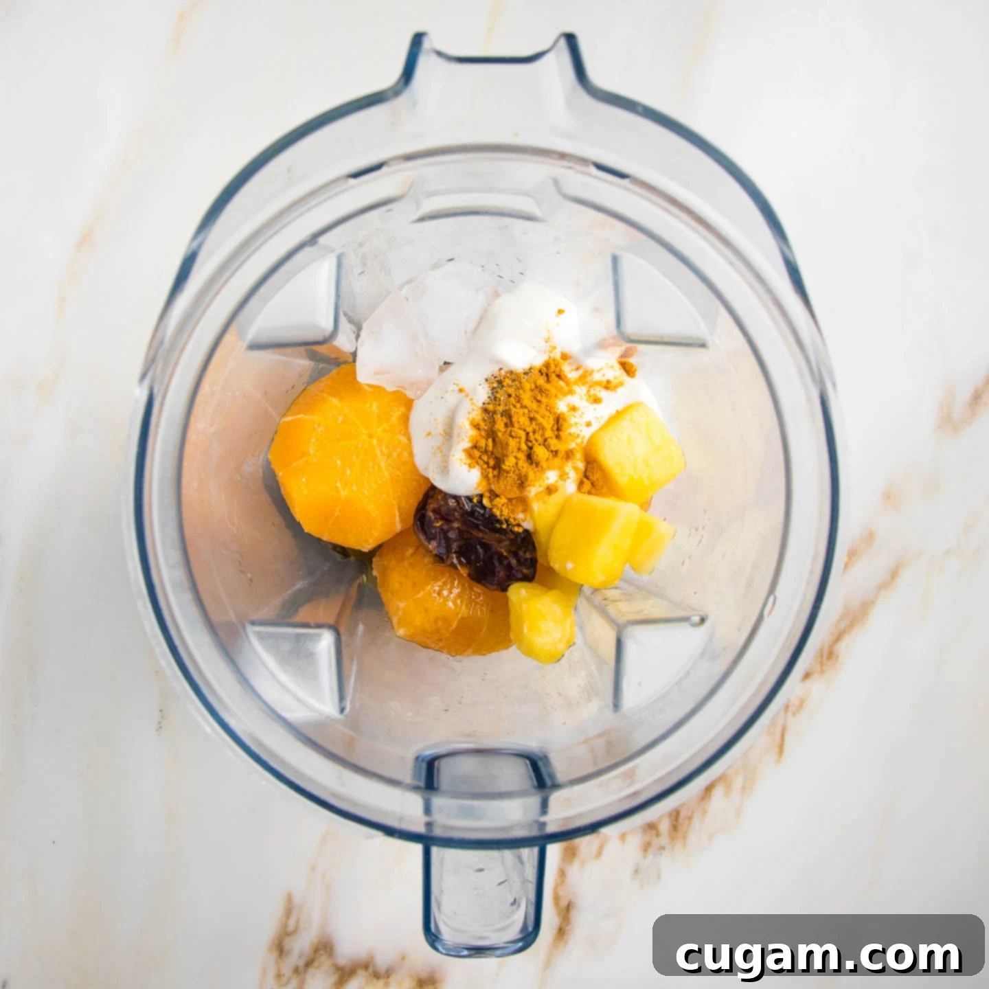 Creamy Orange Bliss 6 Blender pitcher filled with all the smoothie ingredients: peeled oranges, frozen pineapple, plant-based yogurt, a soaked Medjool date, vanilla, turmeric, and black pepper, ready for blending.