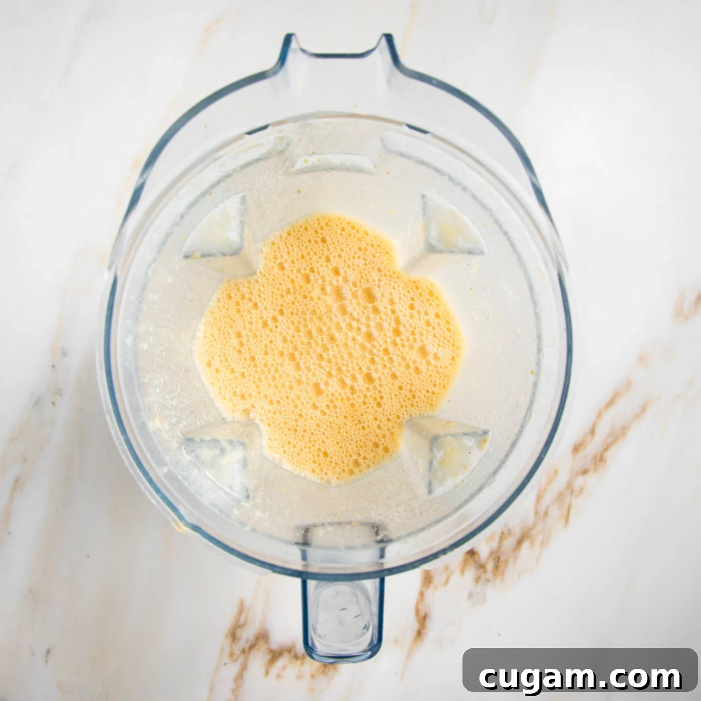 Creamy Orange Bliss 7 A blender pitcher filled with a creamy, frothy orange smoothie, demonstrating the smooth and well-blended consistency achieved.