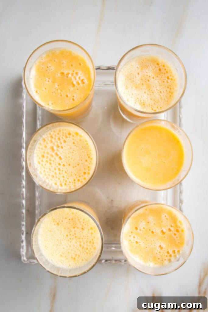 Creamy Orange Bliss 8 Six glasses filled with frothy Orange Julius smoothies arranged neatly on a clear glass serving tray, ready to be enjoyed.