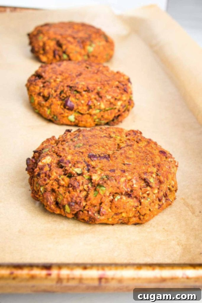Veggie burger patties neatly arranged on a parchment-lined baking sheet, ready to be baked.