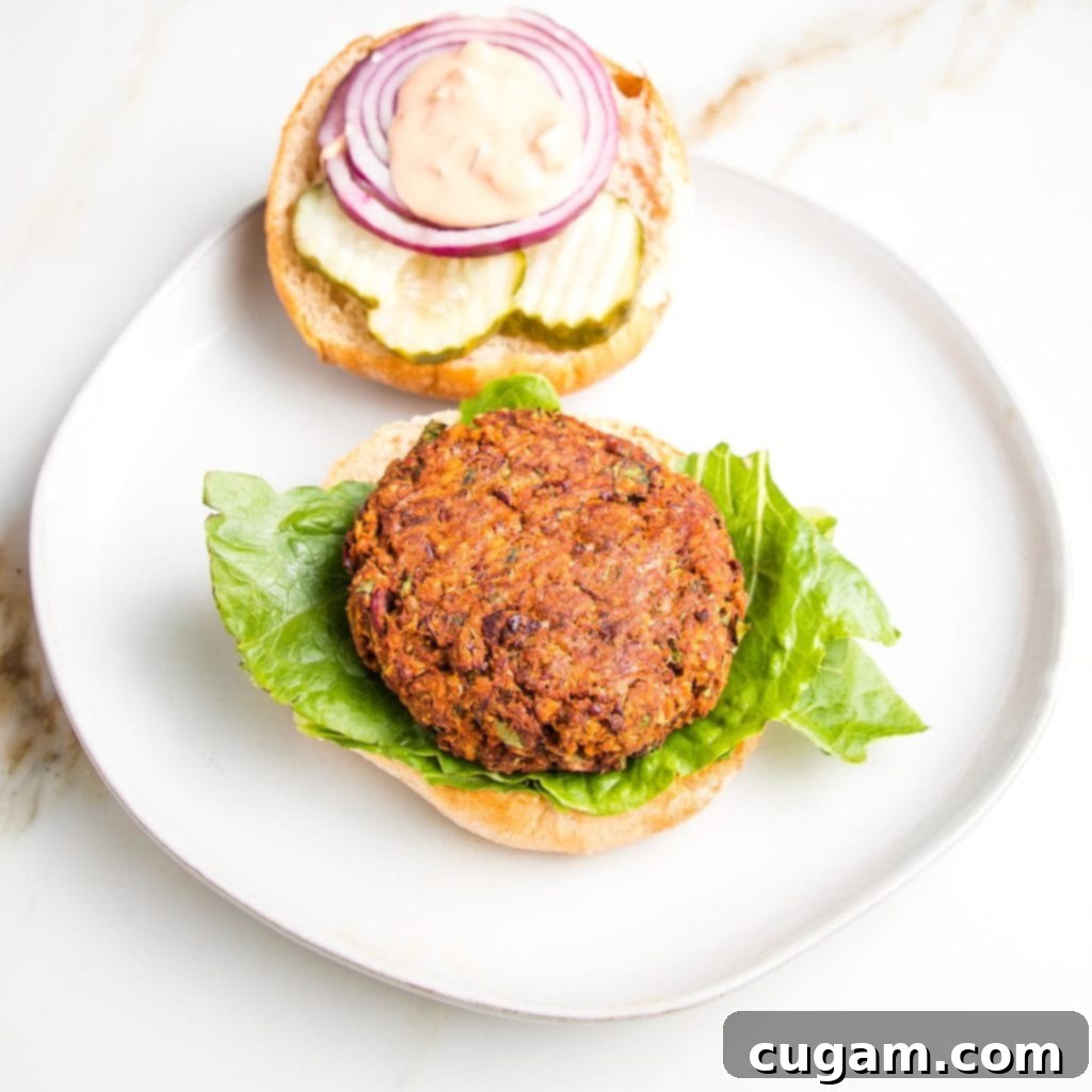 A beautifully presented quinoa veggie burger on a plate, topped with fresh greens and a creamy sauce, ready to be enjoyed.