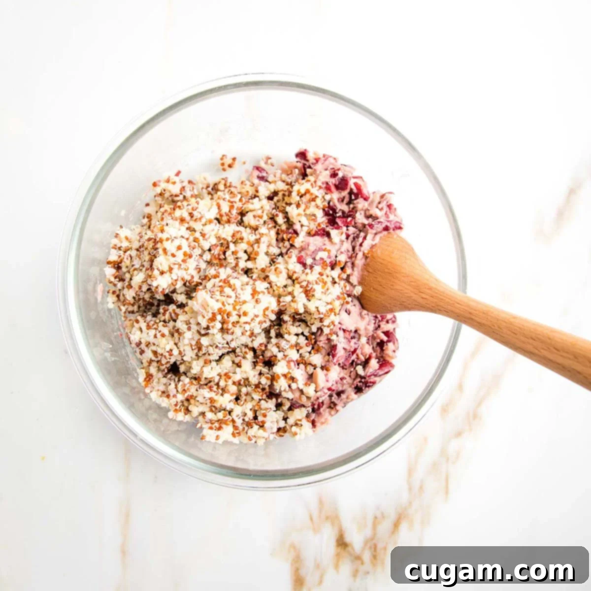 Cooked quinoa and mashed kidney beans perfectly combined in a bowl with a wooden spoon, ready for the next ingredients.