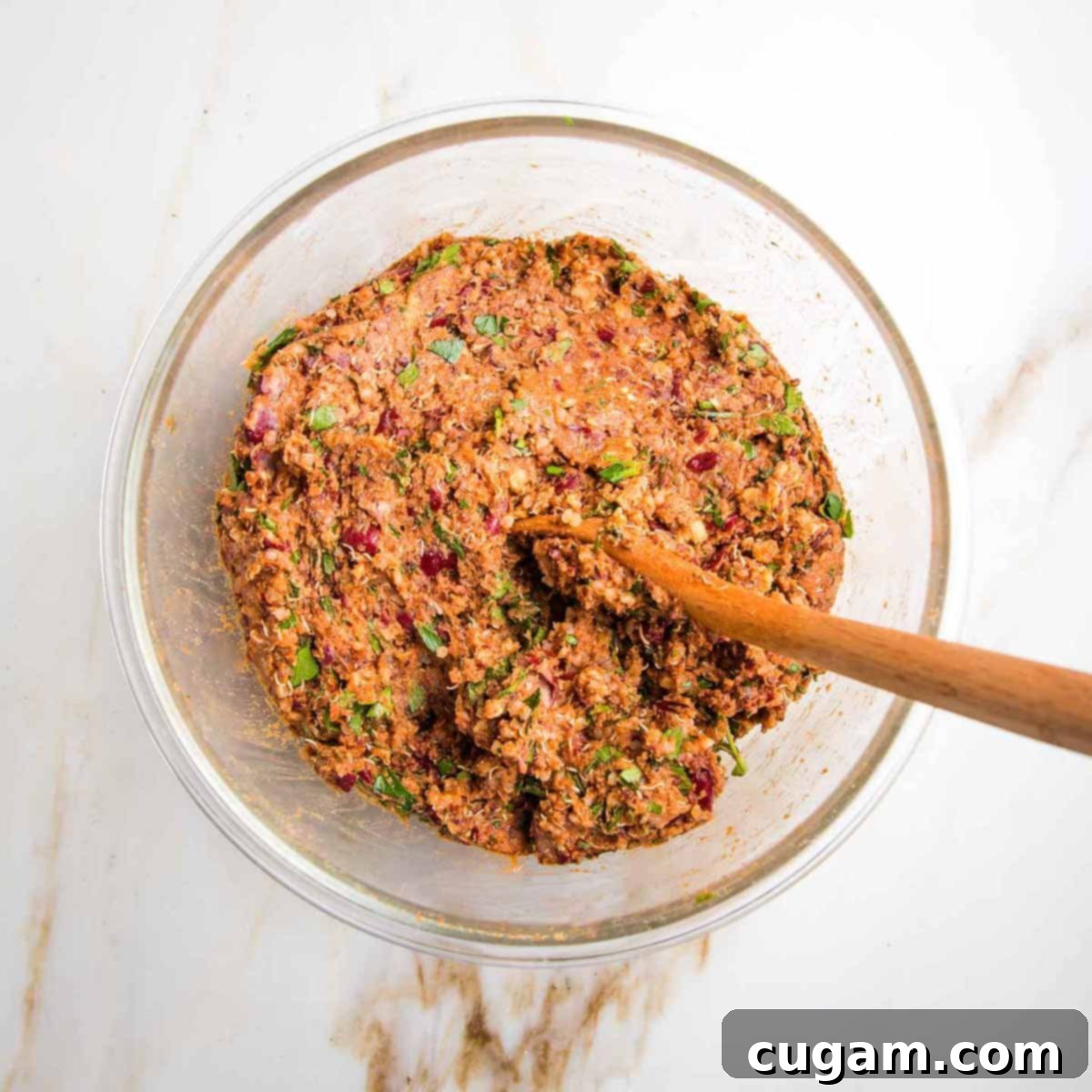 A rich, brownish-red veggie burger batter, a perfect blend of mashed beans, quinoa, spices, and fresh herbs, ready for shaping.