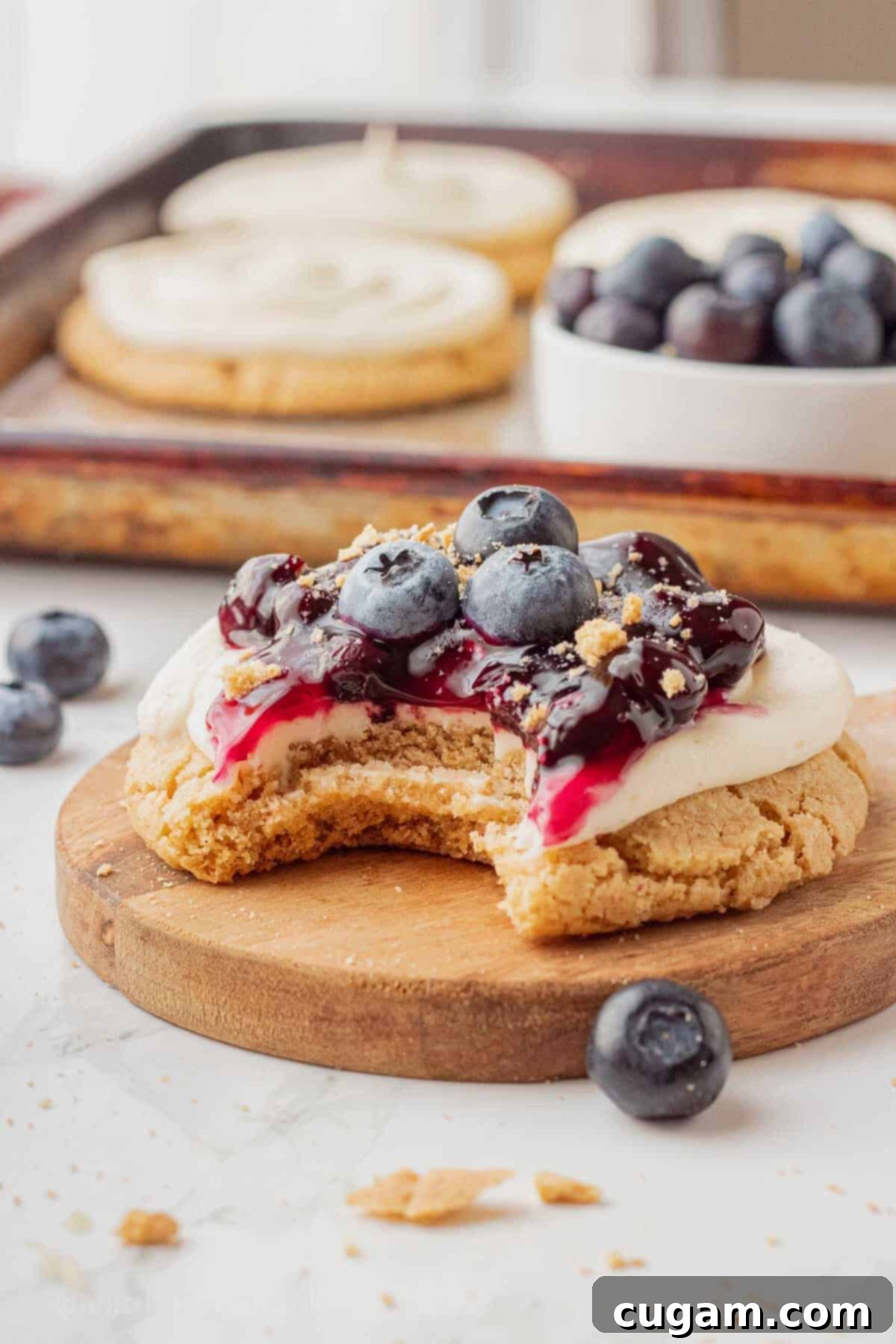 Bite out of blueberry cheesecake cookie on wood cutting board.