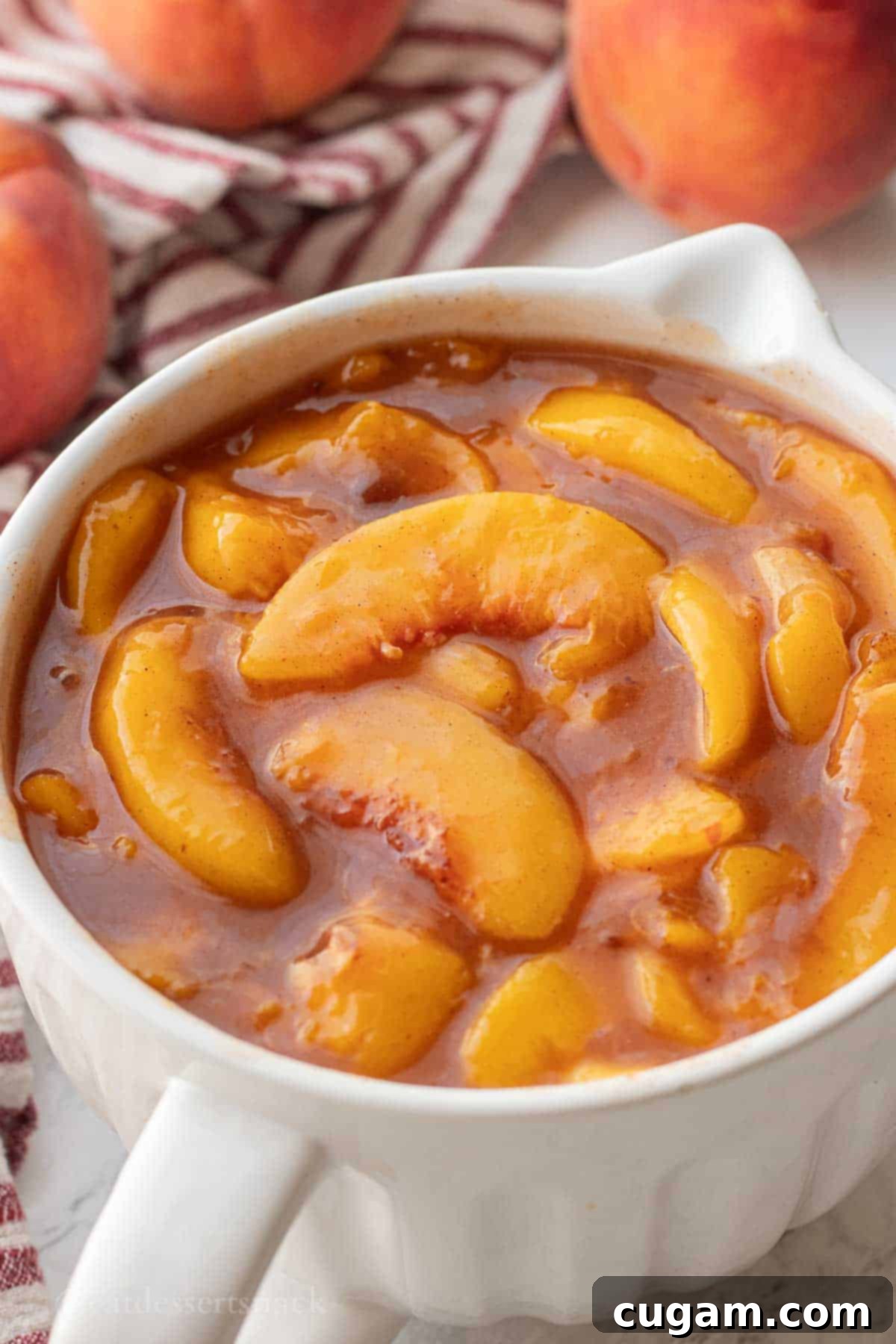 Cooked peach pie filling in a pristine white bowl, showcasing its rich color and thick consistency.