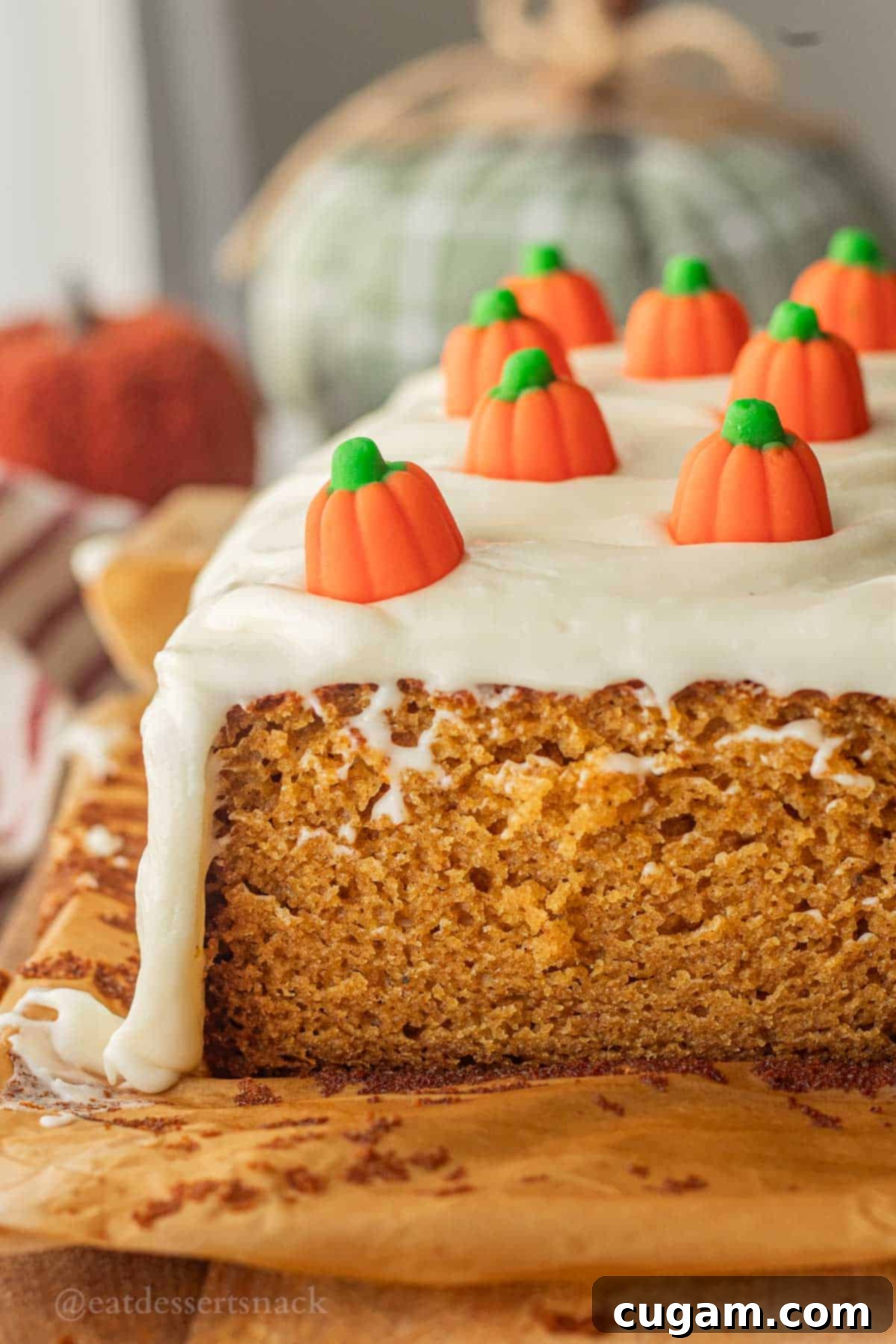 Baked pumpkin bread with cream cheese frosting on parchment paper.
