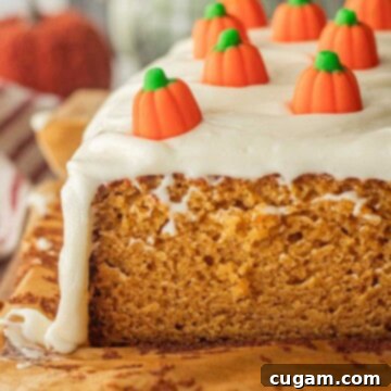 Baked pumpkin bread with cream cheese frosting on parchment paper.