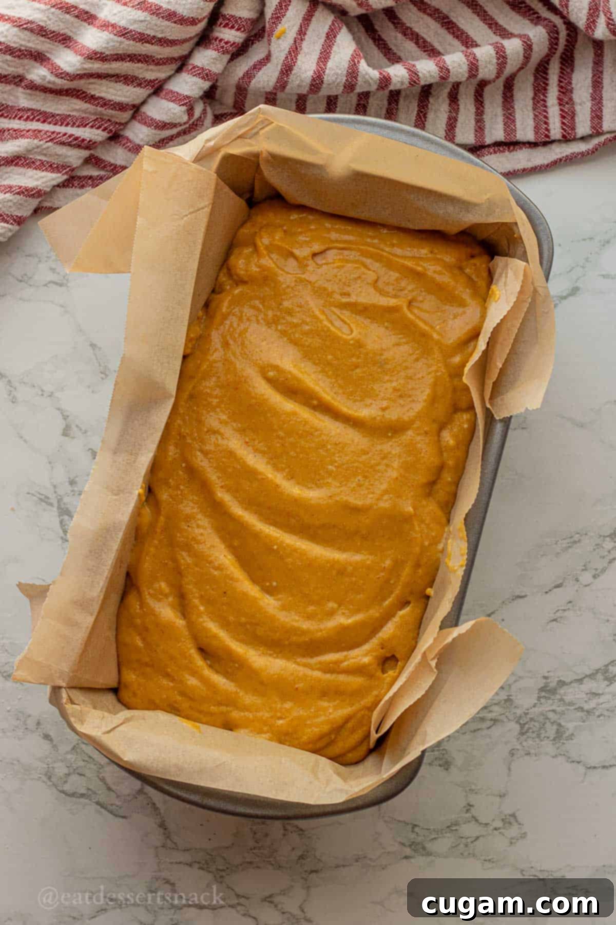 Raw pumpkin bread batter in parchment lined bread pan.