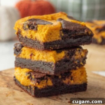 Stacked baked pumpkin cheesecake brownies.