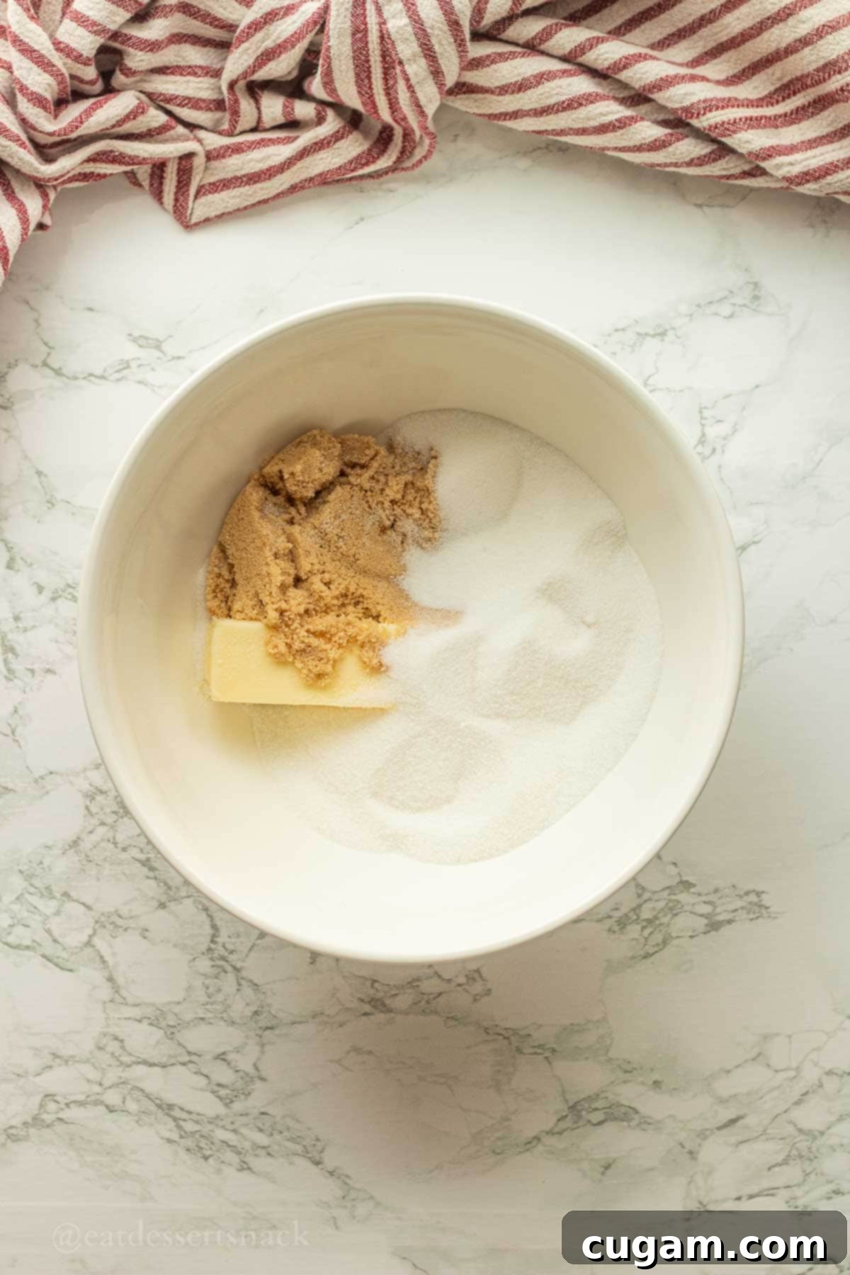 Butter and sugar in bowl on marble countertop, ready for creaming.