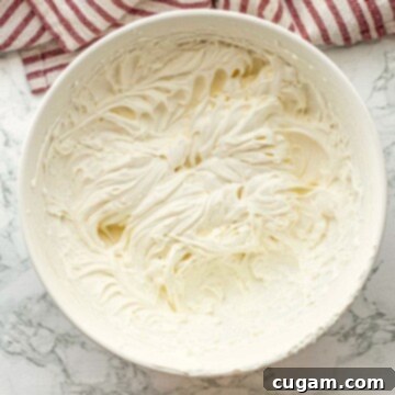 Cloud-Light Cream Cheese Whip 9 Whipped cream cheese topping in bowl on marble countertop.