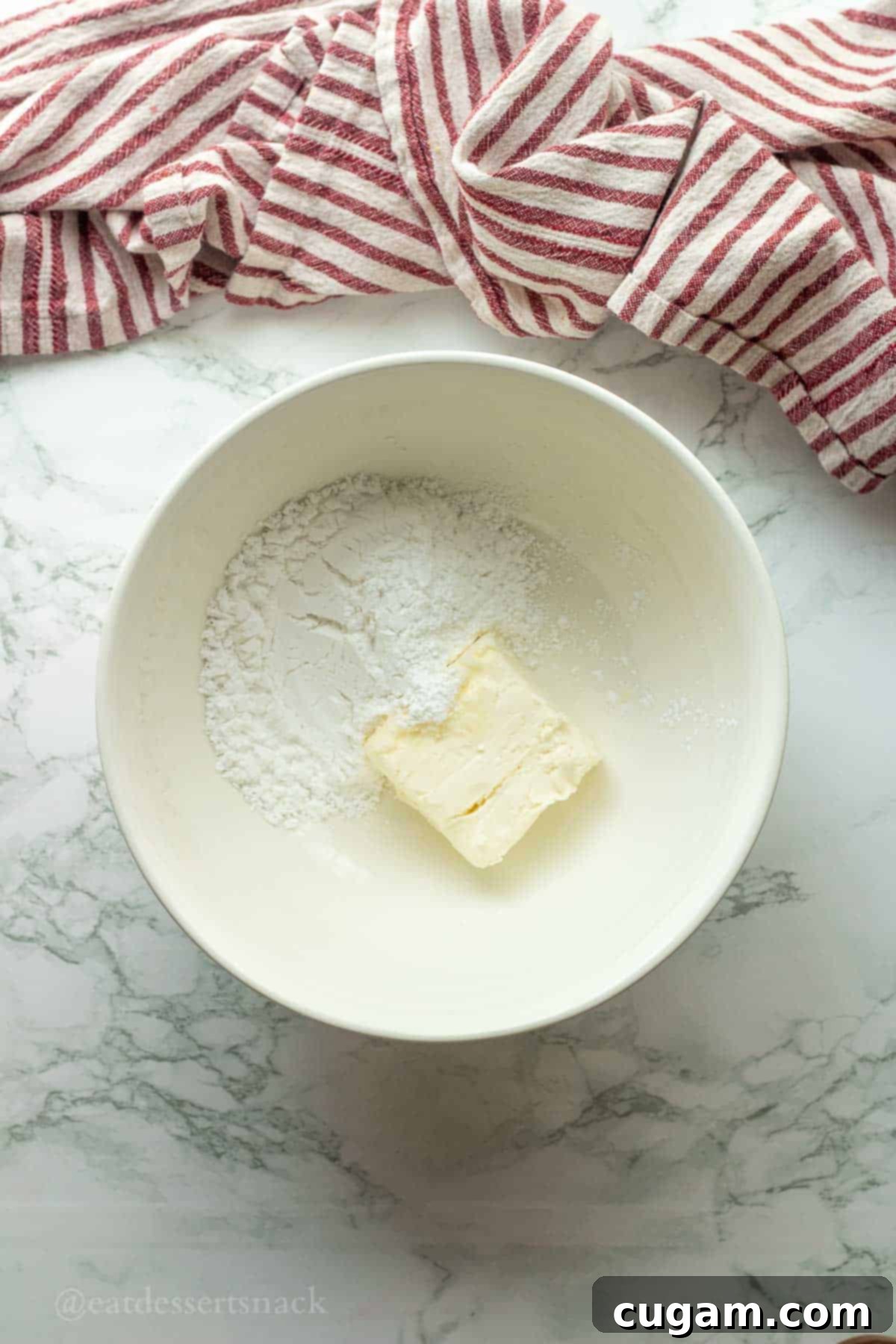 Cloud-Light Cream Cheese Whip 4 Cream cheese and powdered sugar being mixed in a bowl.