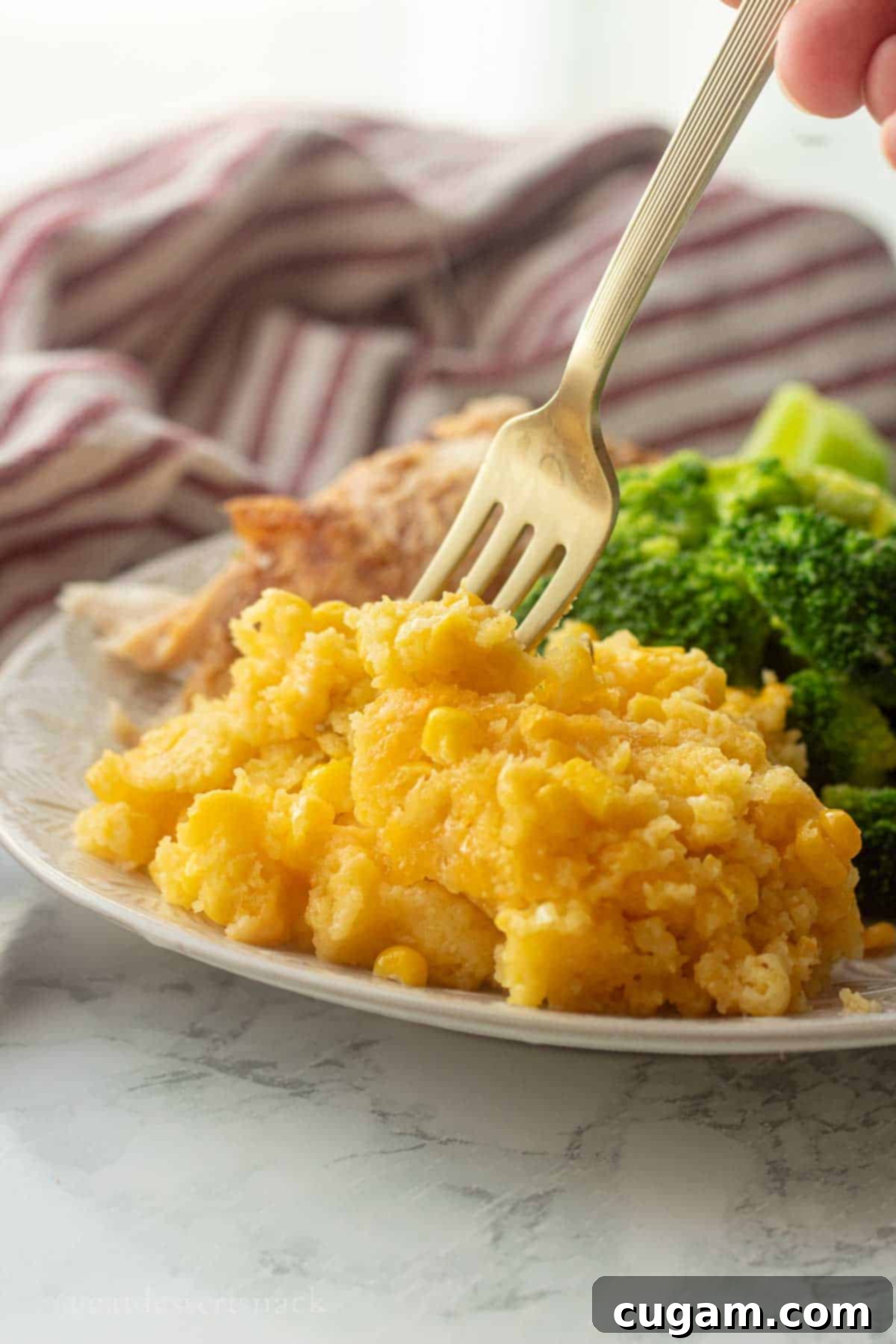 Cooked corn pudding with broccoli and meat on a plate with fork.