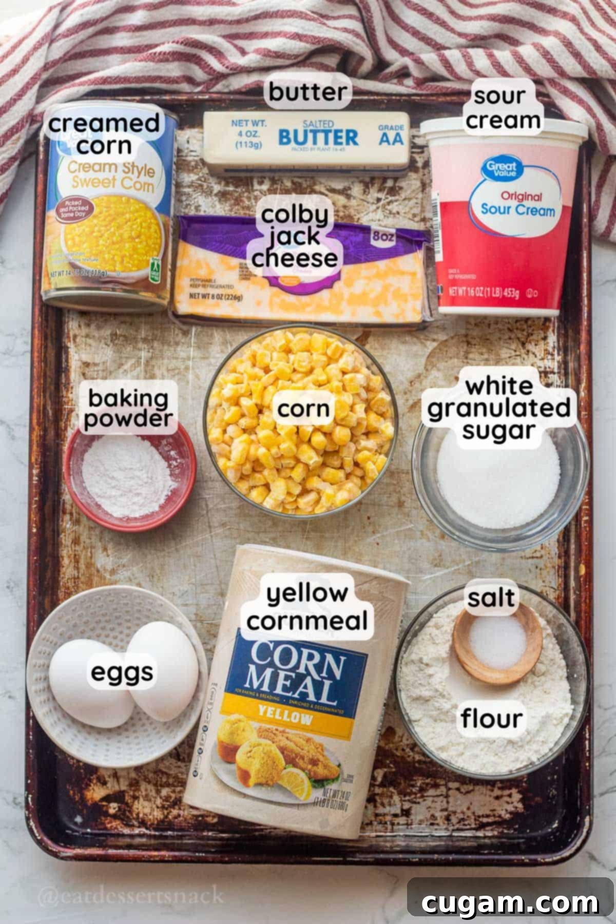 Labeled ingredients for slow cooker cornbread pudding on metal pan.