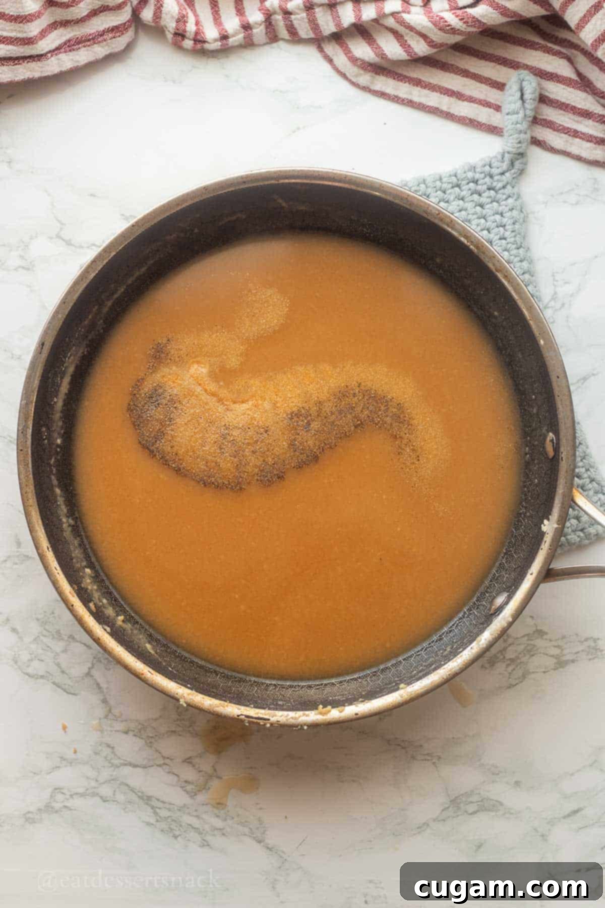 A pan containing broth and various spices, visually representing the final step of seasoning the brown gravy to perfection.