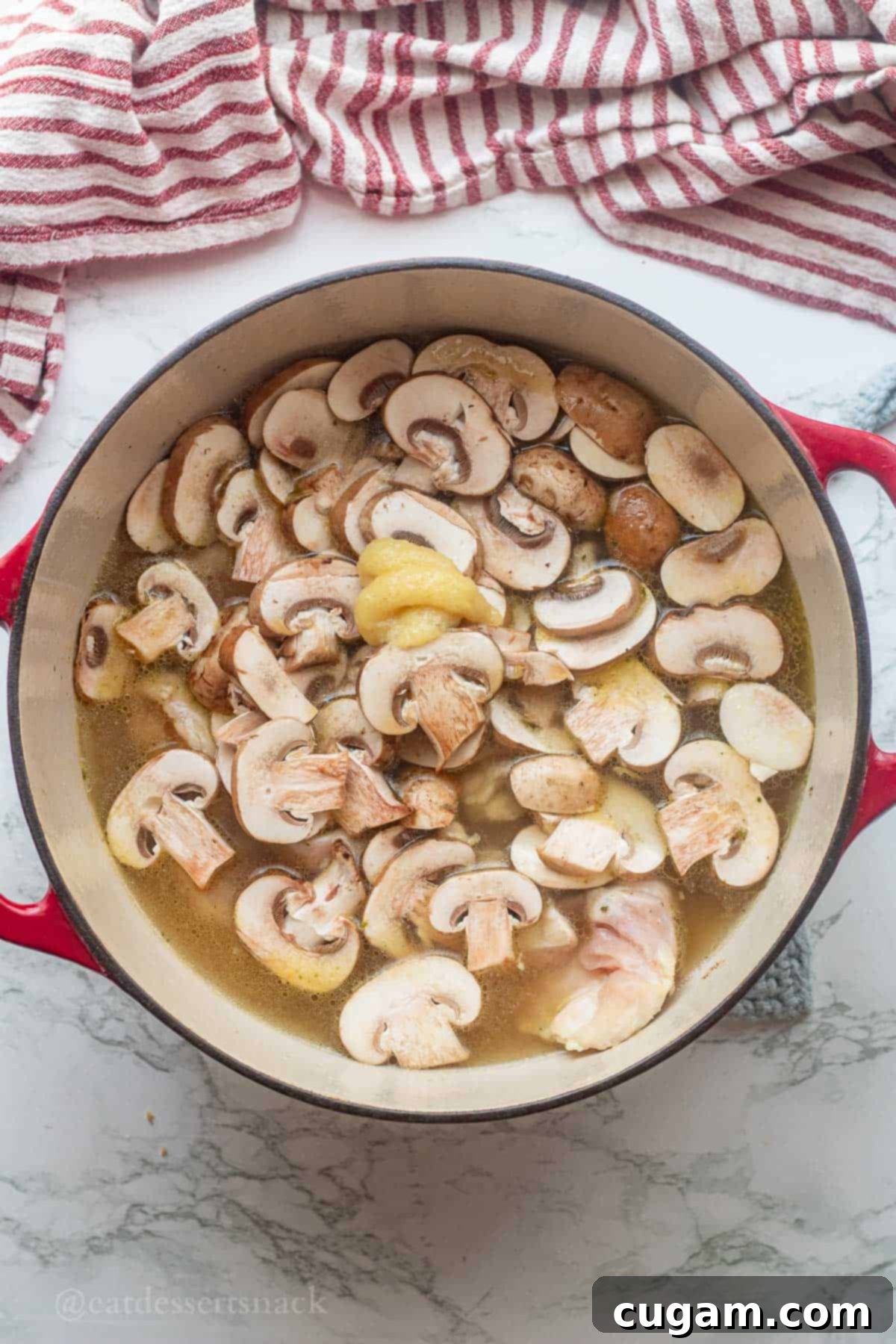 Tom Kha Gai 5 Sliced mushrooms and ginger in pot of chicken broth.