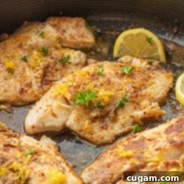 Perfectly Zesty Lemon Pepper Tilapia 8 Cooked tilapia with lemon zest and parsley in pan.