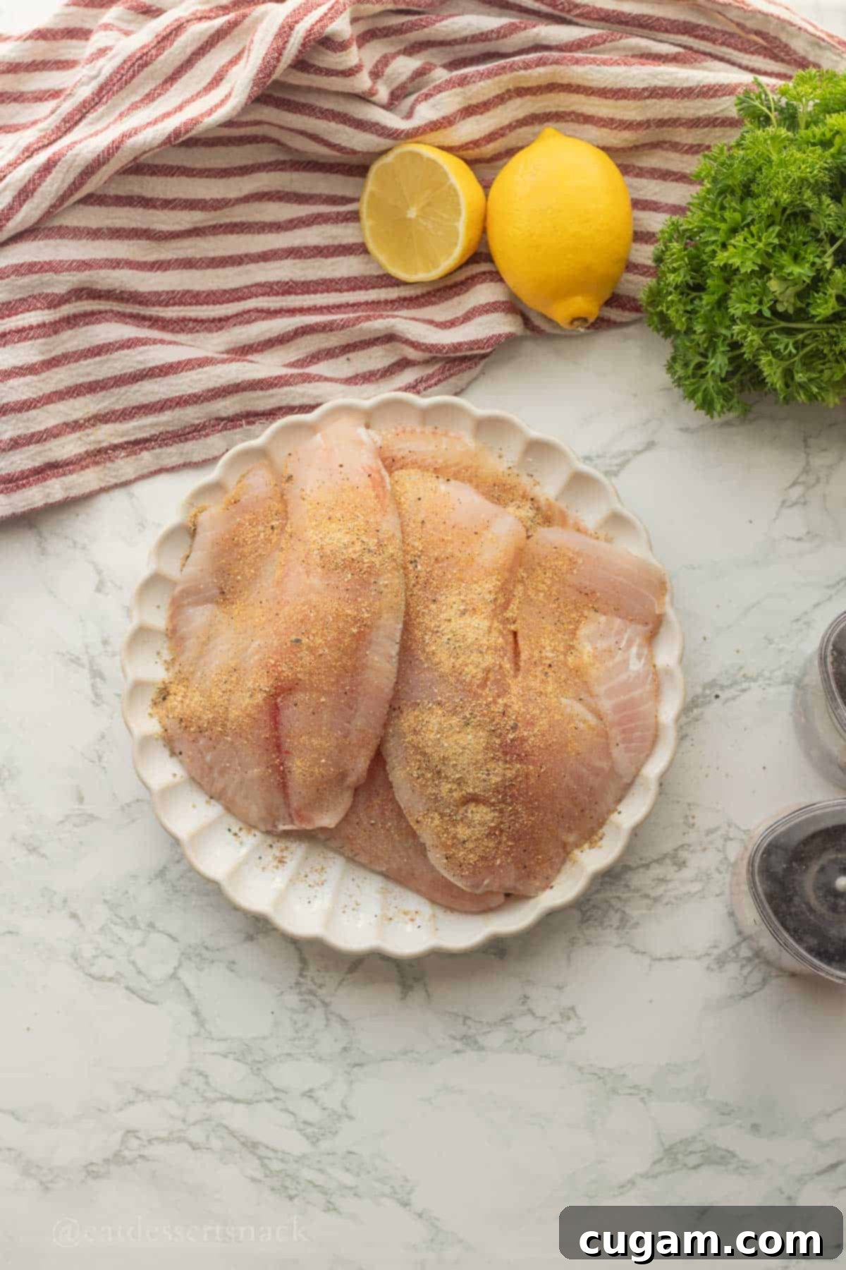 Perfectly Zesty Lemon Pepper Tilapia 5 Raw tilapia seasoned on a plate, ready to be cooked.