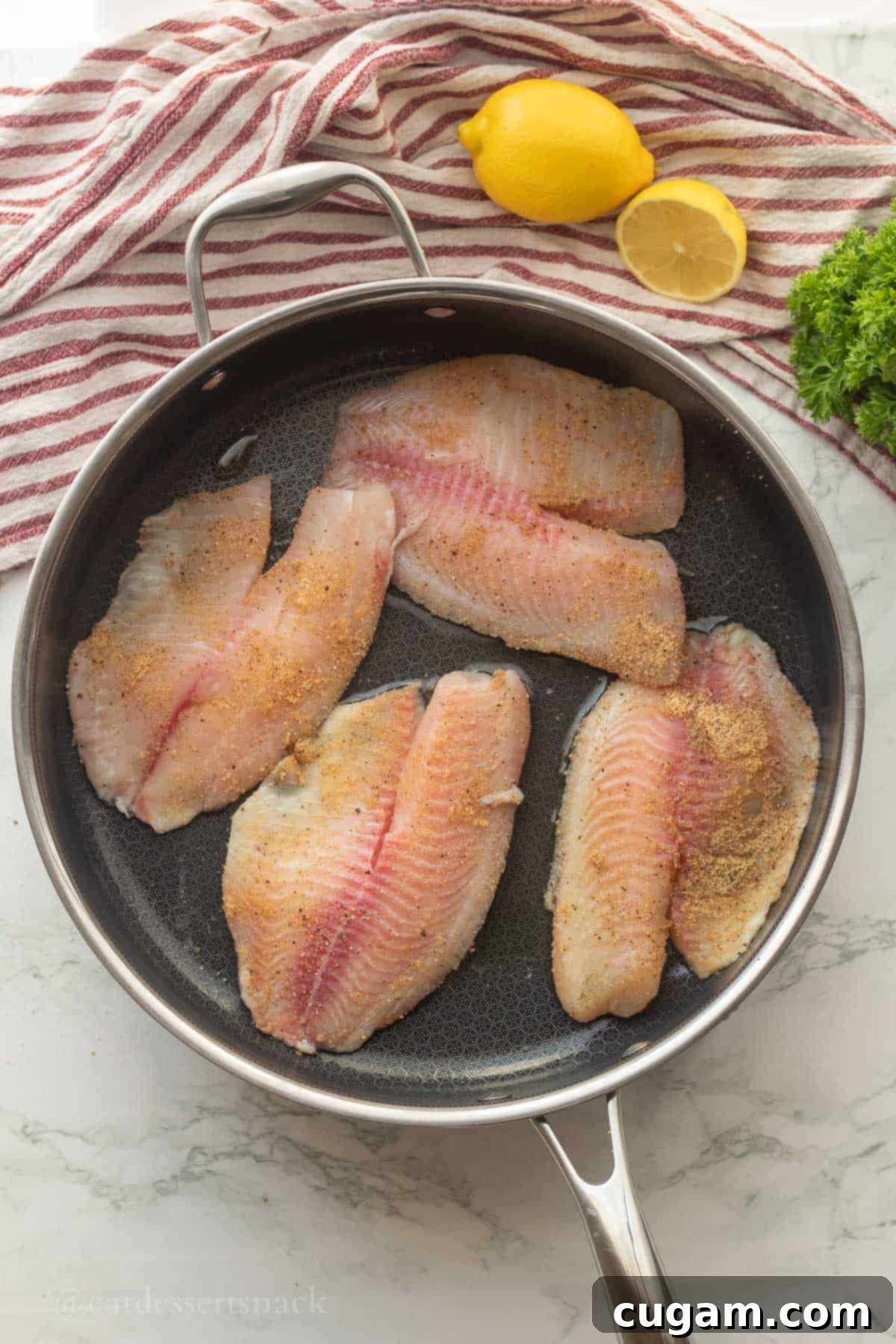 Perfectly Zesty Lemon Pepper Tilapia 6 Raw tilapia cooking in a pan, sizzling in olive oil.