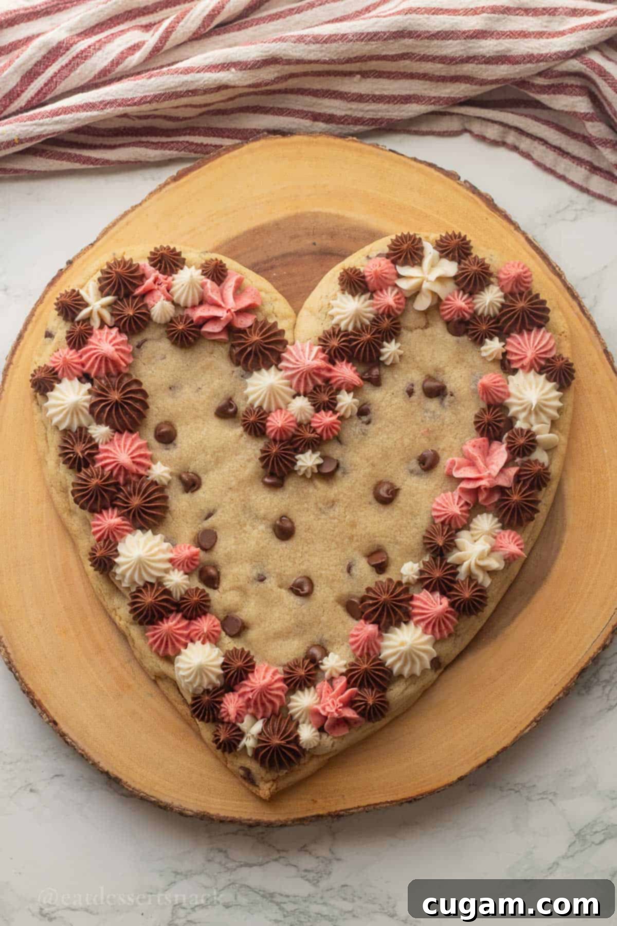 Frosted Heart Cookie Slab 2 Frosted heart-shaped cookie cake on a wood platter, showcasing the three frosting flavors and delicious cookie texture.