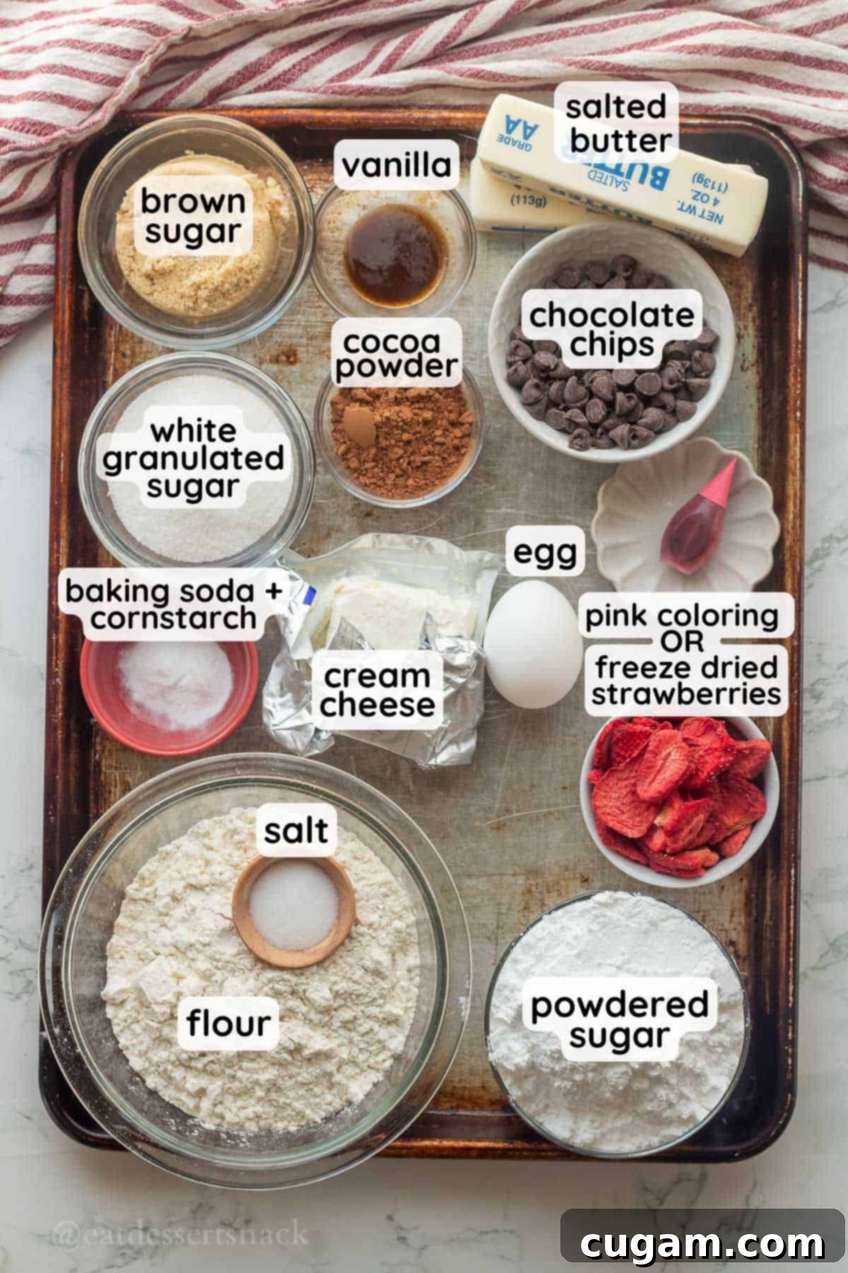 Frosted Heart Cookie Slab 3 Labeled ingredients for heart cookie cake arranged in glass bowls on a metal baking sheet, highlighting the fresh and simple components of the recipe.