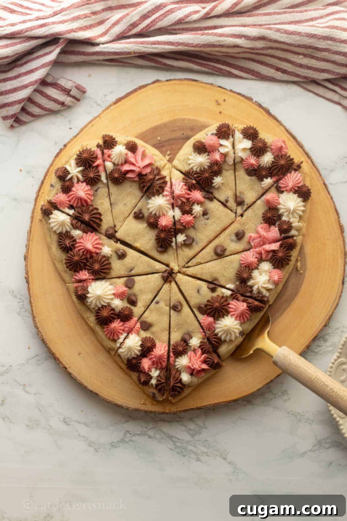 Frosted Heart Cookie Slab 9 Heart cookie cake being sliced with a gold spatula, revealing the cookie texture and layers of frosting.